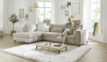 Frau sitzt auf bequemen Sofa und liest Zeitschrift